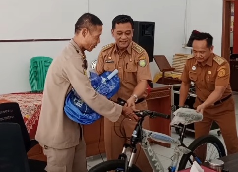 Camat Haurgeulis Rory Firmansyah memberikan hadiah sepeda kepada Maryono saat acara pelepasan purna tugas staf Pol PP
